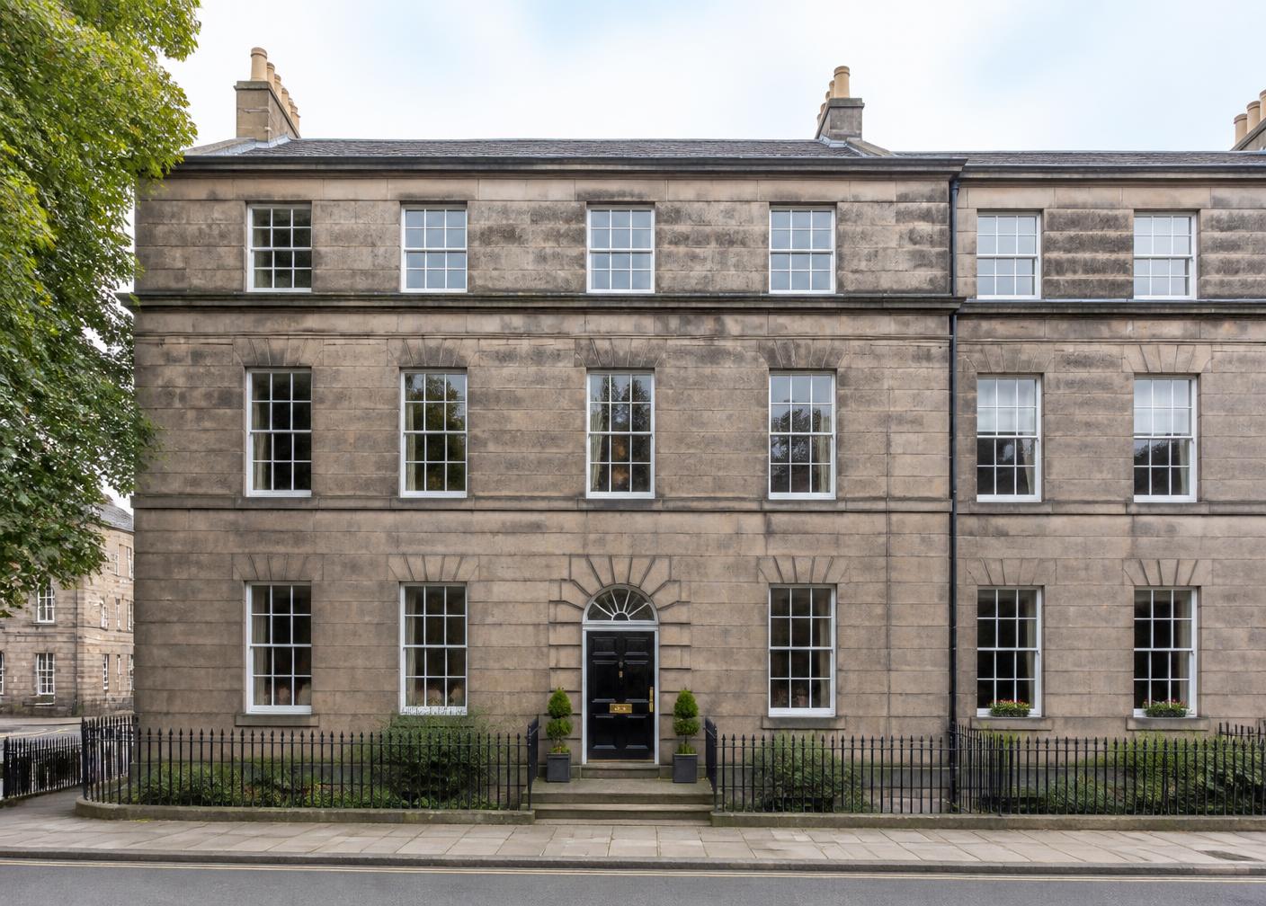 Georgian stone townhouse frontage with black front door and iron railings